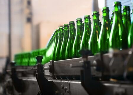 Glass bottles on conveyor belt in beverage facility