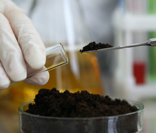 Soil being put into a test tube for environmental lab analysis