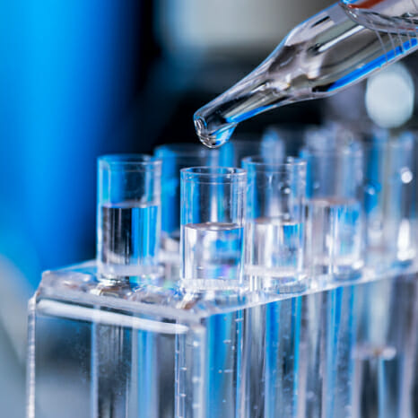 Pipette putting liquid into test tubes in a commercial testing laboratory