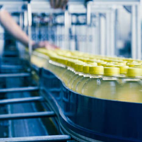 Yellow glass bottles on conveyor belt in beverage facility